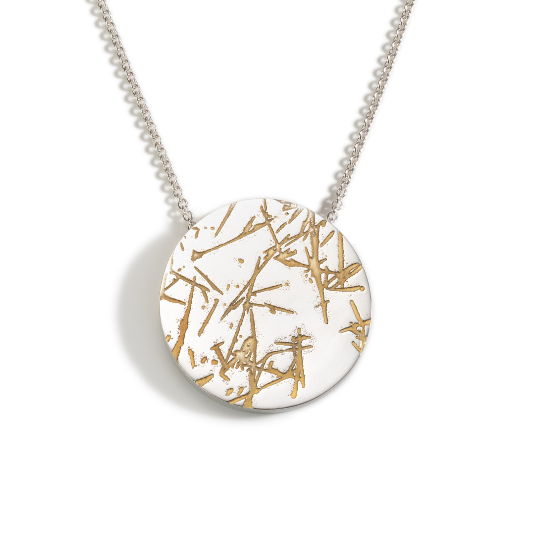 Circular silver statment pendant with etched cracks which have been gold plated